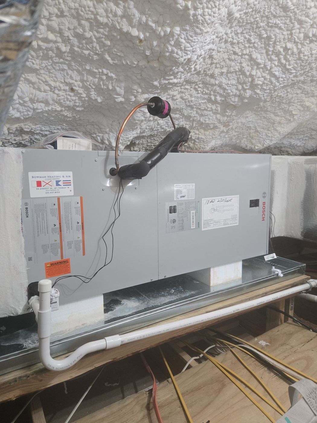 Bosch air handler installed by Bowman Heating & Air — attic installation with Bowman branded sticker, spray foam insulation